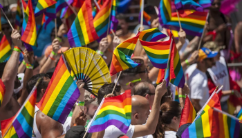a big crowd of people holding pride flags in the air 
